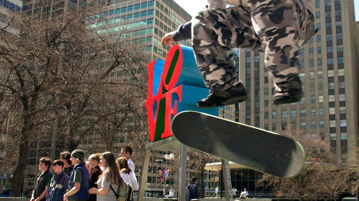  Mike Cole, 14, of Jenkintown, Pa., performs a kick-flip over a trash can in JFK Plaza, or 'Love Park' as it's known to skateboarders, while tourists pose for a photograph in Philadelphia.  (Douglas Bovitt/AP Photo, file) 