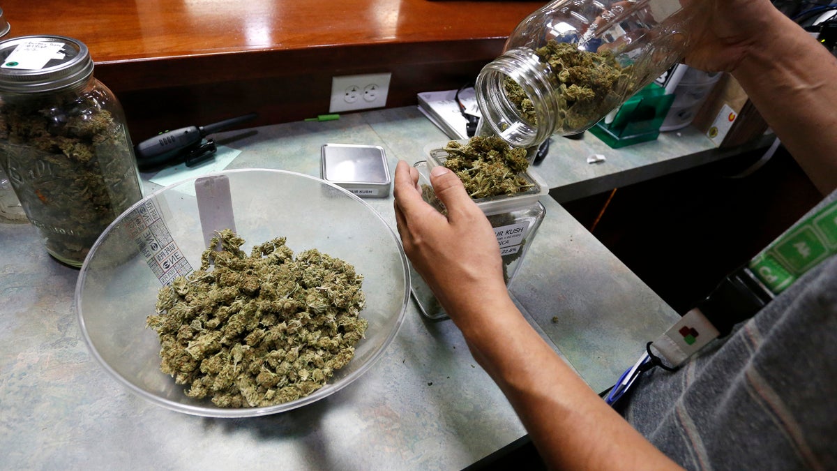 An employee places marijuana for sale into glass containers at The Station