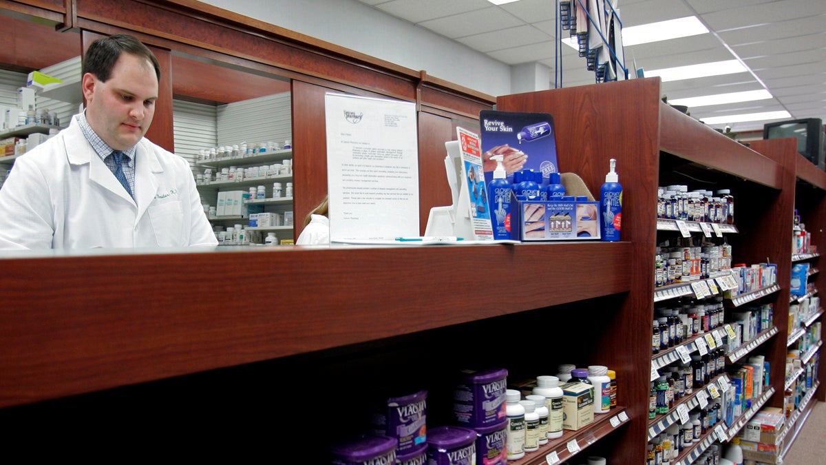 A pharmacist checks on a prescription for a patient behind the counter (Kiichiro Sato/AP Photo, file) 