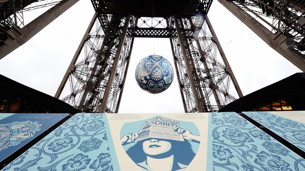  American street artist Shepard Fairey, aka Obey's latest piece, 'Earth Crisis', a giant sphere themed on environment hangs between the first and second floor of the Eiffel Tower in Paris, Friday, Nov. 20, 2015. Obey's art piece which weighs 2,3 tons will be displayed until Nov. 26 as Paris will be hosting the climate change conference from Nov. 30-Dec. 11, 2015. (Binta Epelly/AP Photo) 