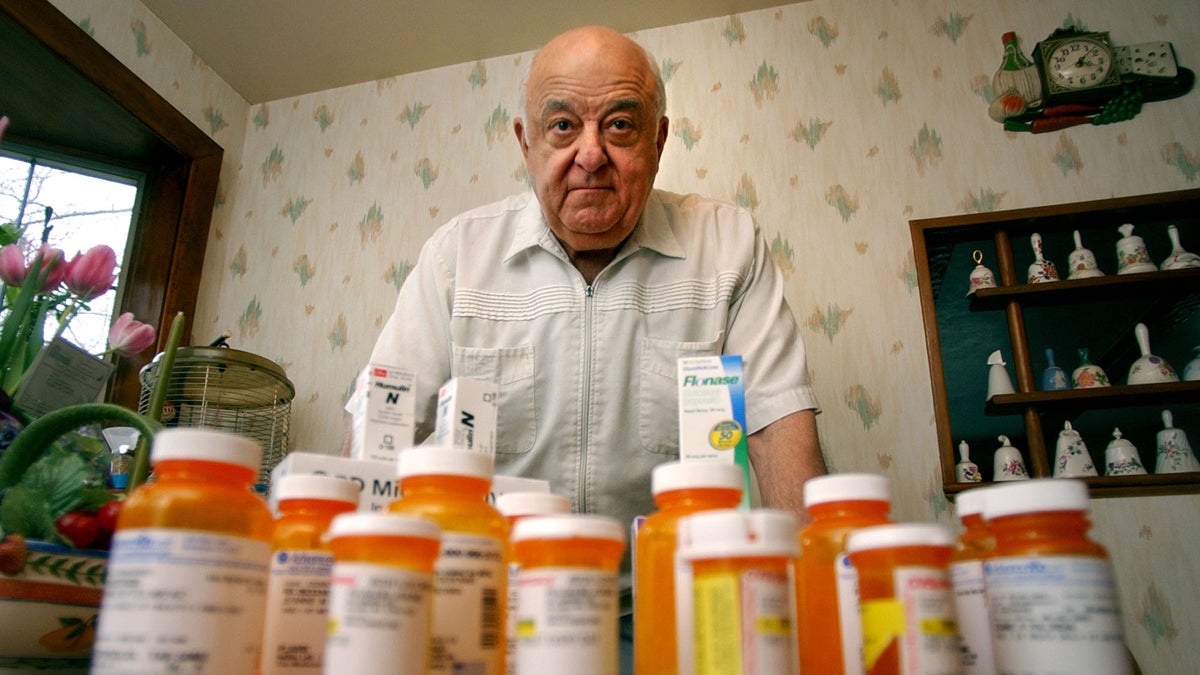  A man poses in the kitchen of his home with his wife's daily medication. (Charles Krupa/AP Photo) 