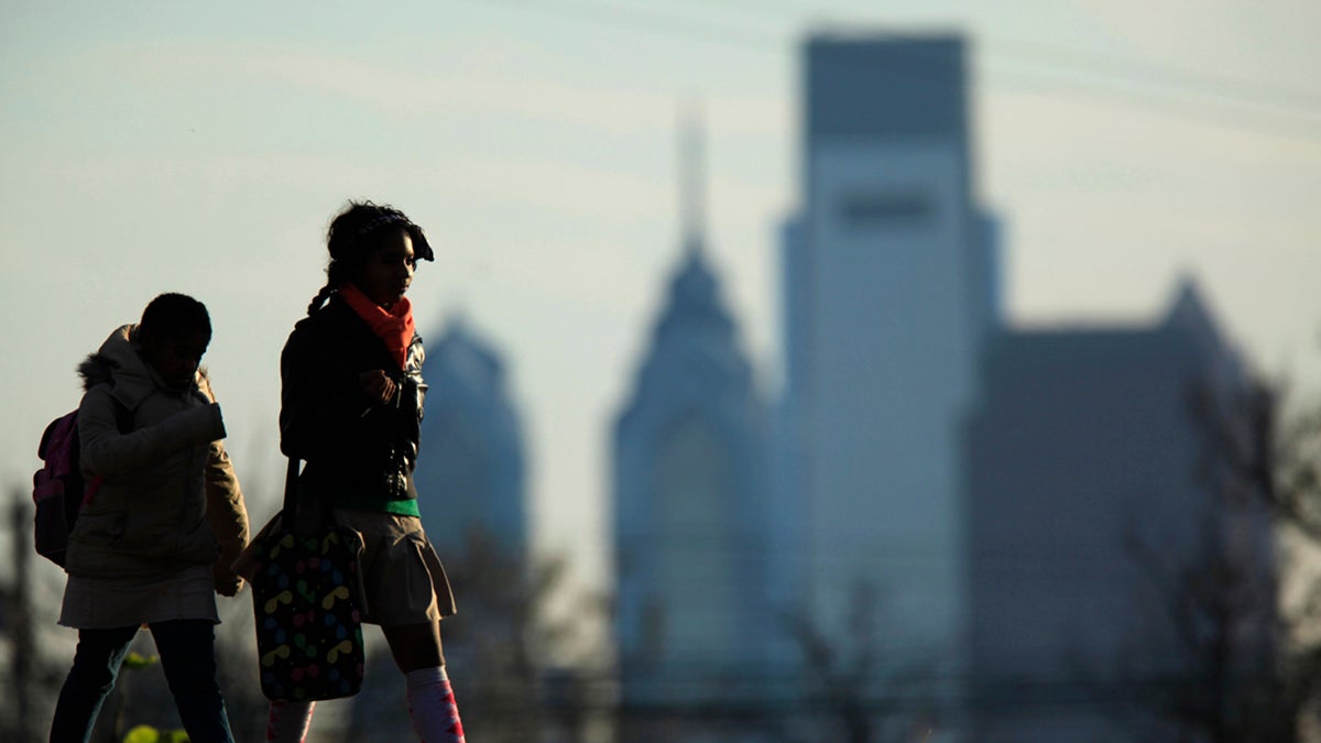 People walk in view of the city skyline in Philadelphia.