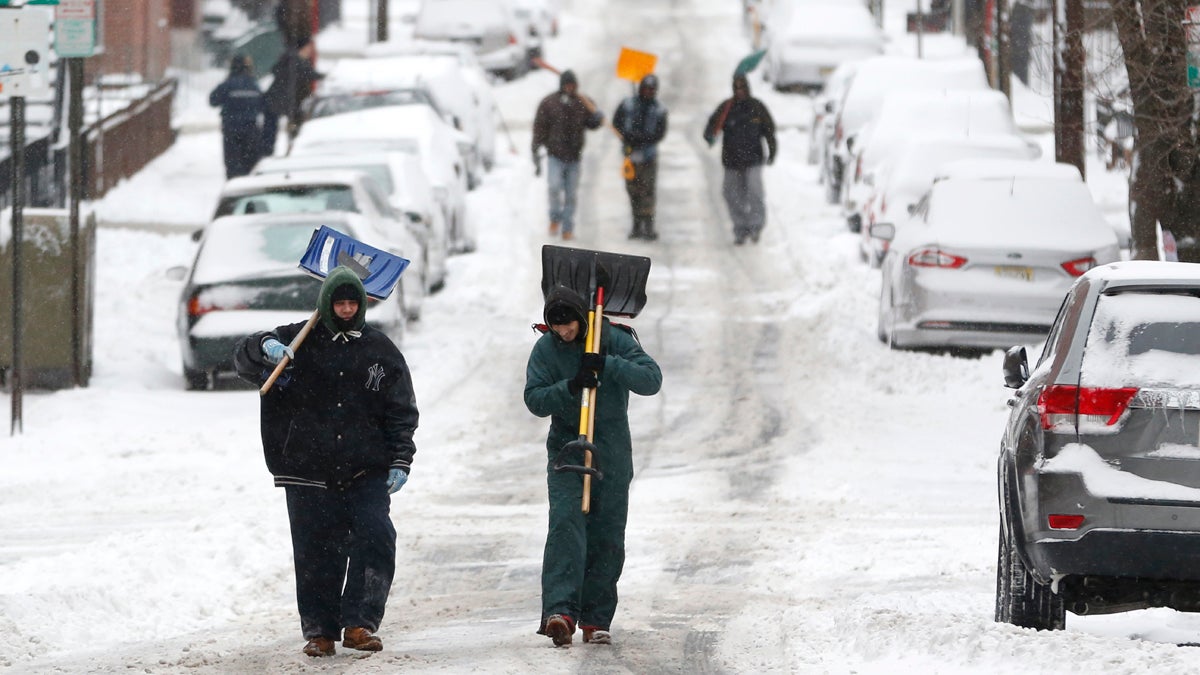 Men carry shovels as they walk on a snow covered road after an overnight snowstorm. (Julio Cortez/AP Photo)
