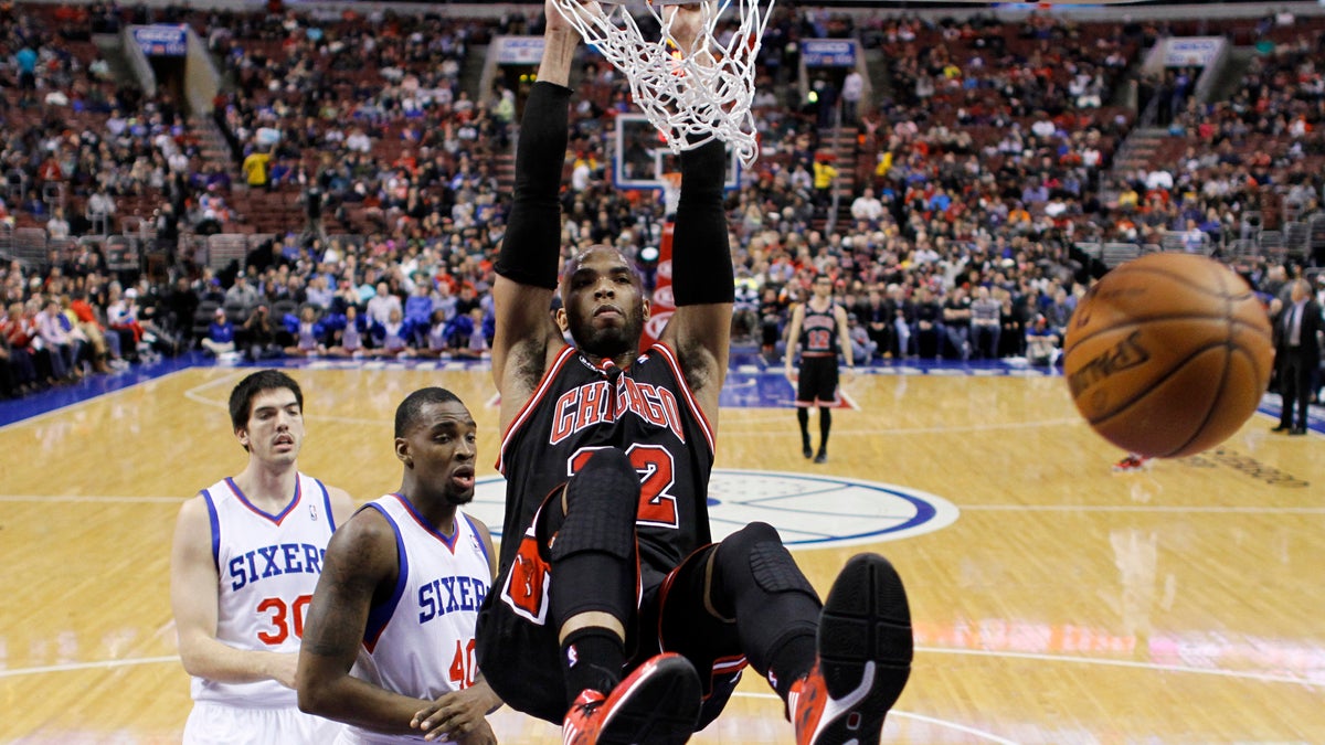  Chicago Bulls' Taj Gibson (22) hangs on the rim after dunking the ball against Philadelphia 76ers' Jarvis Varnado (40) and Byron Mullens (30) during the first half of an NBA basketball game, Wednesday, March 19, 2014, in Philadelphia. (Matt Slocum/AP Photo) 