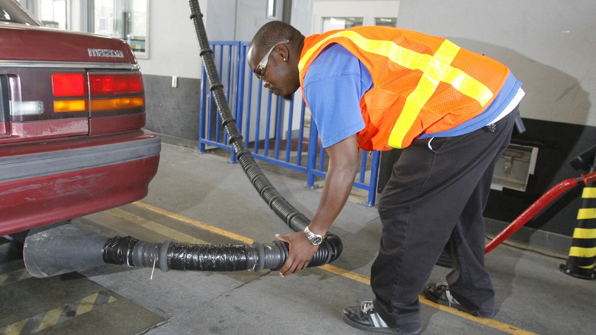 A vehicle inspector conducts a tailpipe emission test. (Rick Bowmer/AP Photo)