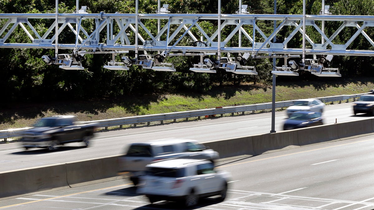 Cars pass under toll sensor gantries hanging over the Massachusetts Turnpike
