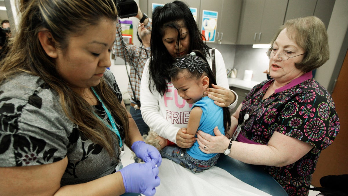Nurses give a 4-year-old a whooping cough booster shot, as she is held by her mother at a health clinic (Ted S. Warren/AP Photo, file) 