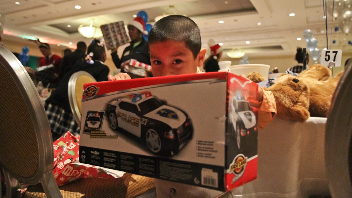 Christian Tellez of St. Agnes school receives a gift form Santa’s elves at the Archbishop’s Christmas Party. (Kimberly Paynter/WHYY)