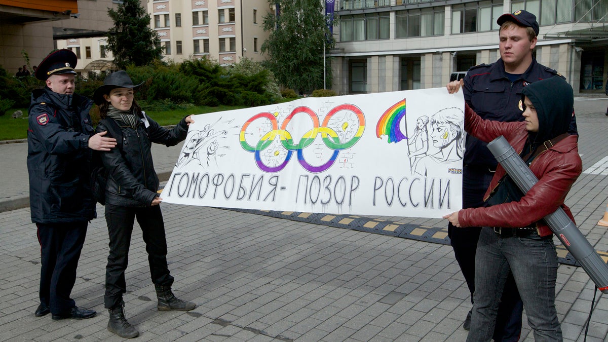  Police officers detain two gay rights activists holding a poster reading 