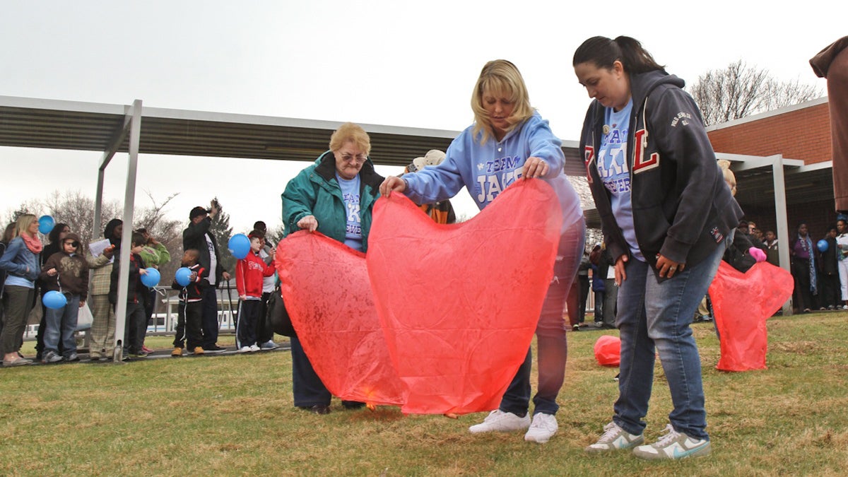  Jessica Harkins (center) and friend Sara Woodington (right) prepare a paper heart lantern to float away in honor of Harkins' son, Jake. (Kimberly Paynter/WHYY) 