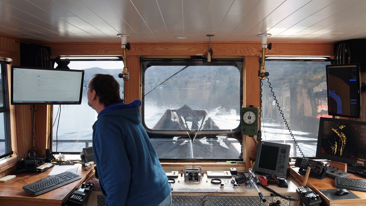 Captain Matthew Baumgartner checks a monitor in the wheelhouse of the D.L. Johnson as it moves a coal barge along the Ohio River.  (Ryan Loew/For Keystone Crossroads)