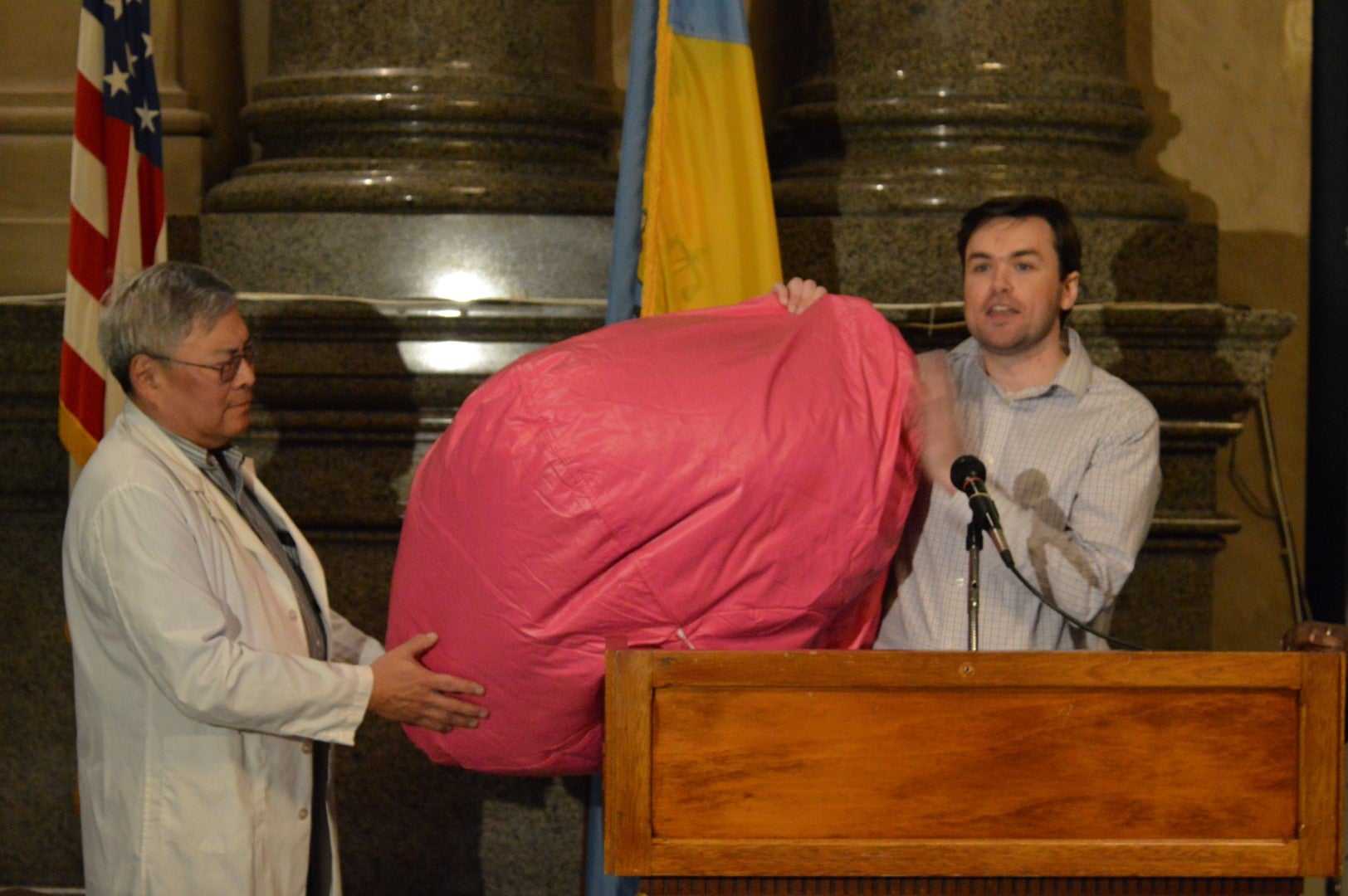 Dr. Walter Tsu of Physicians for Social Responsibility and Michael Roles of Pennsylvania Public Interest Research Group  display a beanbag deemed dangerous because it can easily rip open. It is one item mentioned in the annual 'Trouble in Toyland' report. (Tom MacDonald/WHYY)