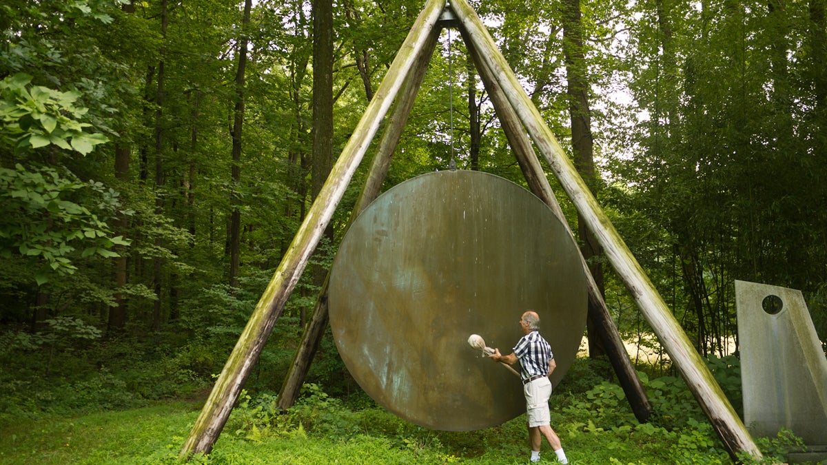  Harry Bertoia's son, Val, strikes a gong with a canvas-wrapped stick. The gong is one of Bertoia's sound sculptures at the family farmhouse in Berks County. (Charlie Kaier/WHYY) 