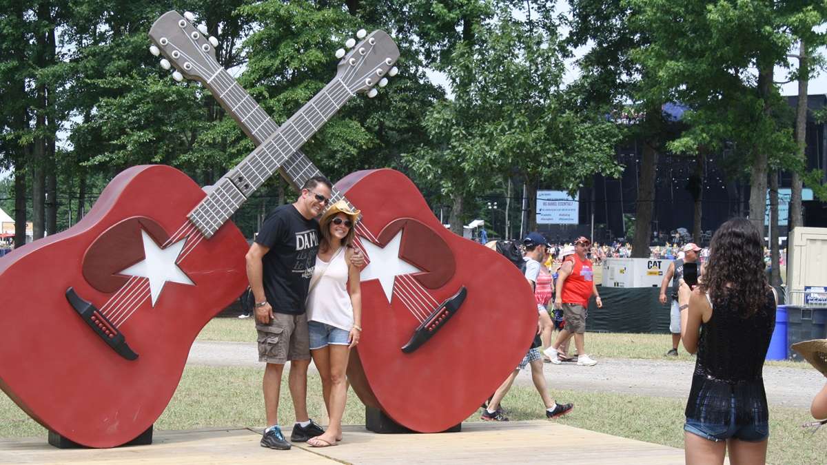  Country music fans pose for pictures in front of Big Barrel's signature crossed guitars. There will be no follow up to last year's inaugural festival. (Mark Eichmann/WHYY) 