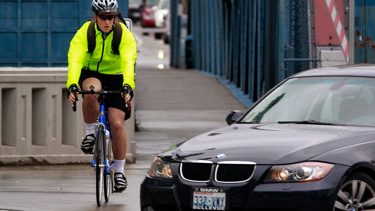  A bicyclist commuting during rush hour keeps an eye on a car turning in front of him in Seattle, Washington. (AP File Photo/Elaine Thompson) 