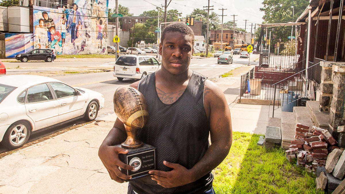  Dawayne Young, who finds himself at the middle of an athletic-eligibility controversy, holds a trophy he received for being the top overall performer at the Next Level Nation Football Camp. (Brad Larrison/for NewsWorks) 