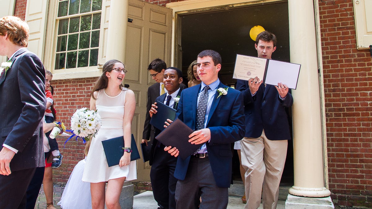 Benjamin Trotto, right, shows off his diploma as he exits the meeting house. (Brad Larrison/for NewsWorks)