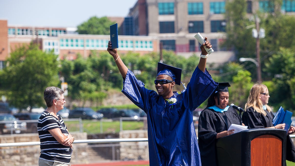 Kytone Goyco holds up his diploma at commencement Tuesday. (Brad Larrison/for NewsWorks)