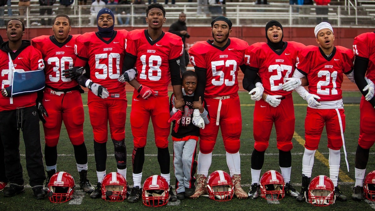 The Imhotep Panthers lock arms before taking the field in Saturday's PIAA AAA City Championship game against Archbishop Wood. (Brad Larrison/fo NewsWorks)