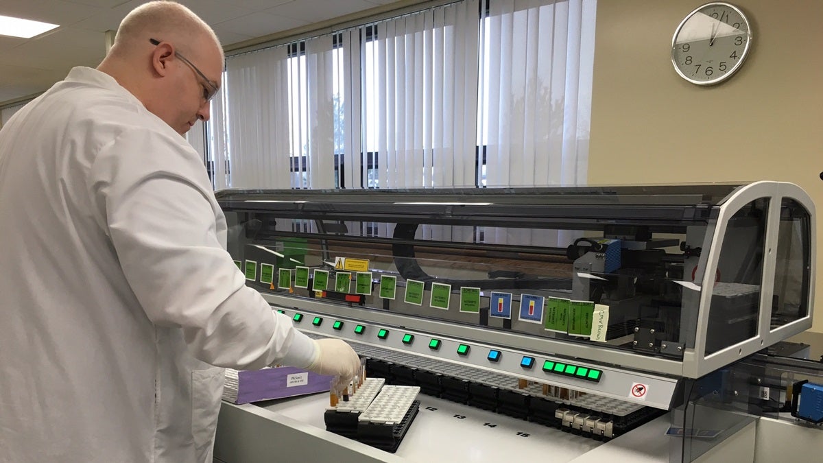  A Blood Bank worker loads samples of blood into the new automated track system. (Mark Eichmann/WHYY) 