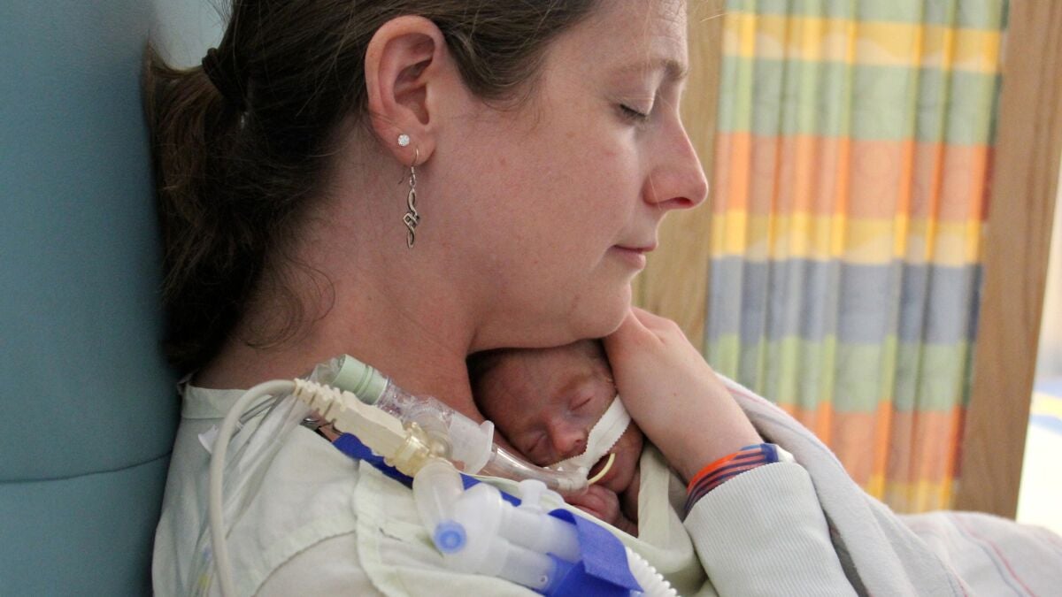 Brenna Denney hold her son, Gavin, to her chest. It's a rare treat. His mother must devide her time between triplets who were born prematurely. (Emma Lee/WHYY)