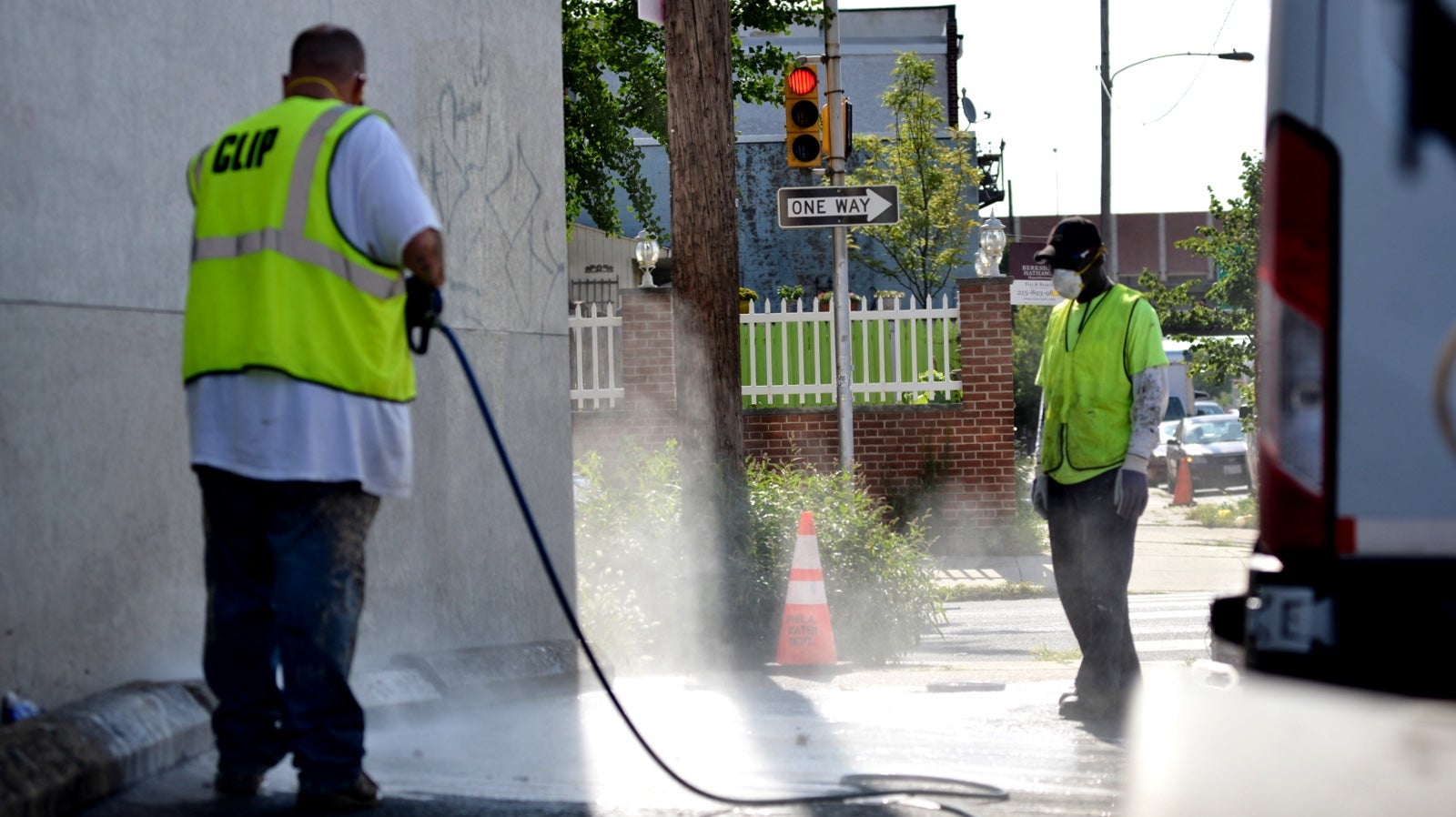 City workers Tim Farnon and Jonathan Hurt remove graffiti from a wall on Washington Avenue in Philadelphia. (Bastiaan Slabbers for NewsWorks)