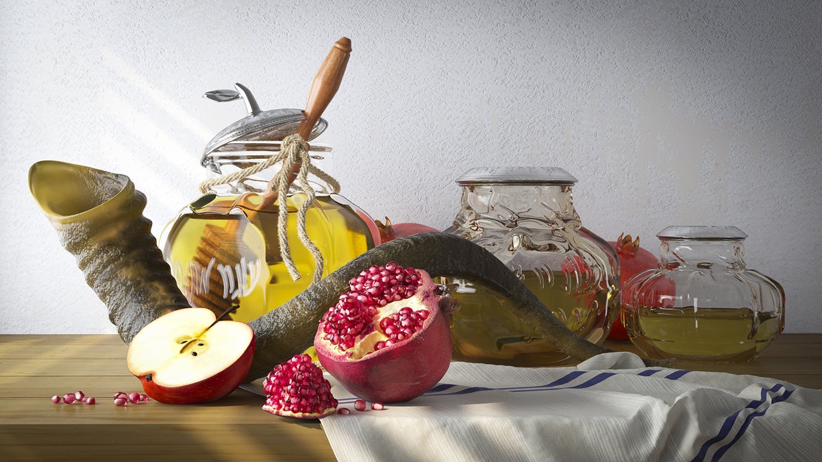 A table is staged for a Rosh Hashana photo including a honey jar with apples