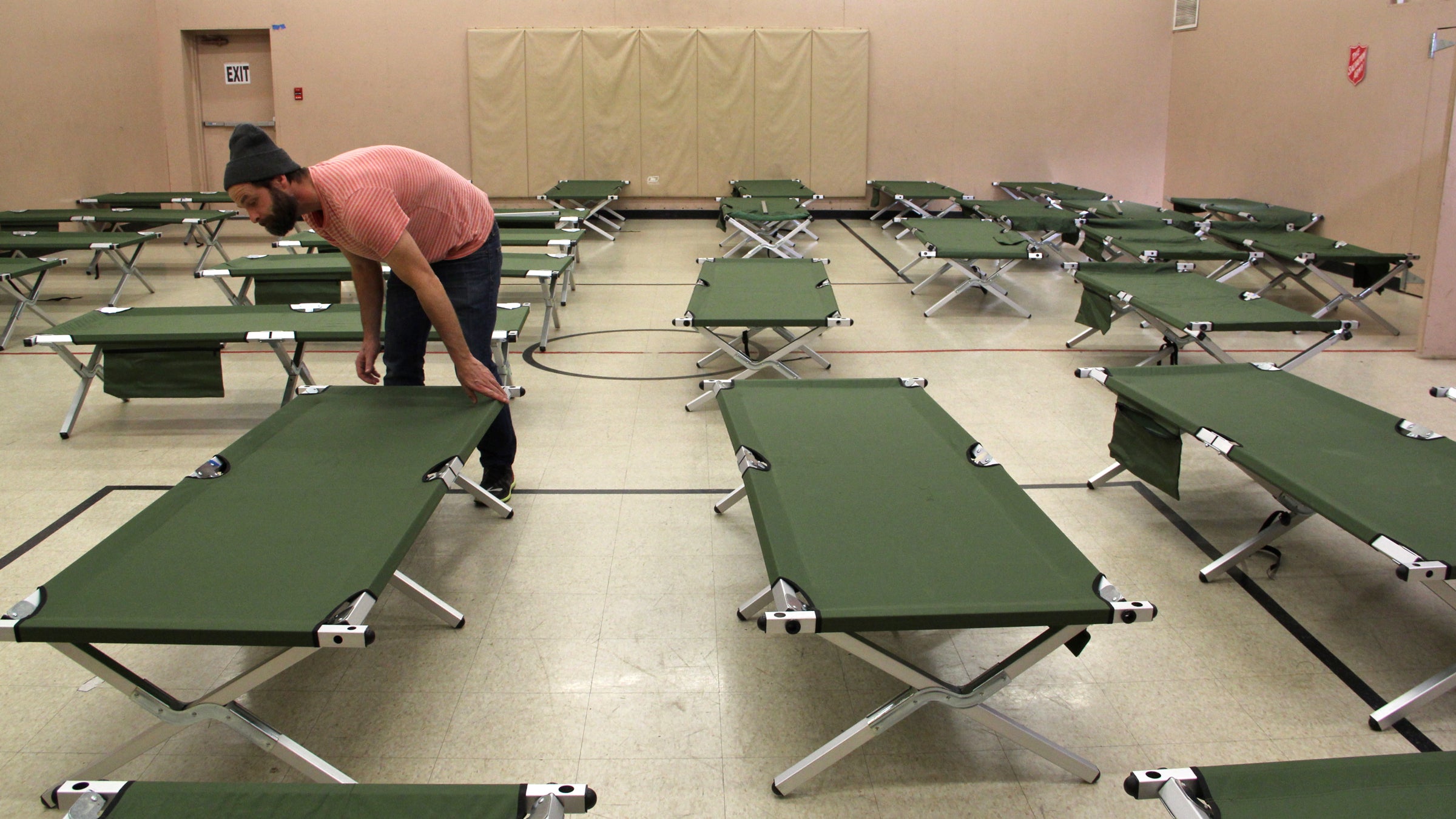 Joel Snyder, housing case manager for the Salvation Army in Norristown, sets up cots for the homeless in the organization's basement gym. (Emma Lee/WHYY) 