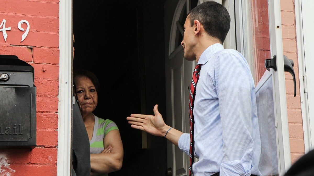 Camden Superintendent Paymon Rouhanifard talks to parents Charlie and Milagros Marrero in Camden's Lanning Square neighborhood. (Kimberly Paynter/WHYY)