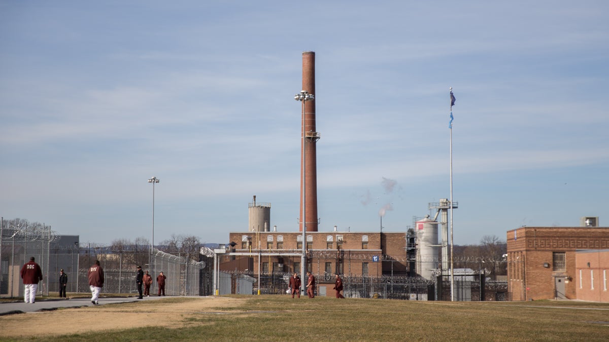Prisoners walk the yard at Camp Hill State Correctional Institution. The Pennsylvania Department of Corrections (DOC) announced five prisons were being considered for closure. Camp Hill SCI expects to hold more prisoners due to closures. (Lindsay Lazarski/WHYY)