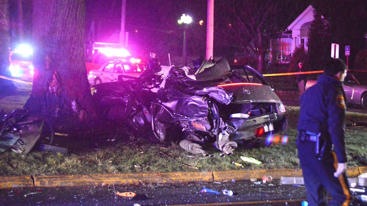 A badly damaged stolen Cadillac rests next to a tree in Newport. The driver was killed crashing the car during a police chase. (John Jankowski/for NewsWorks)