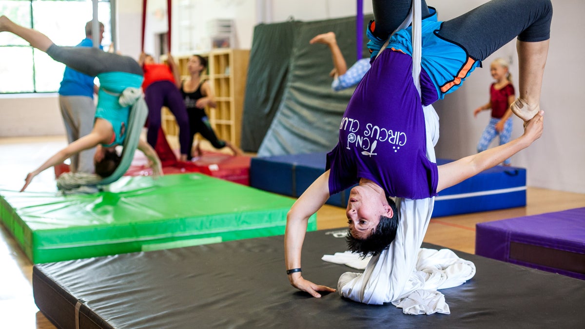 Sandra Leith hangs upside down during the trapeze lesson. (Brad Larrison/for NewsWorks)