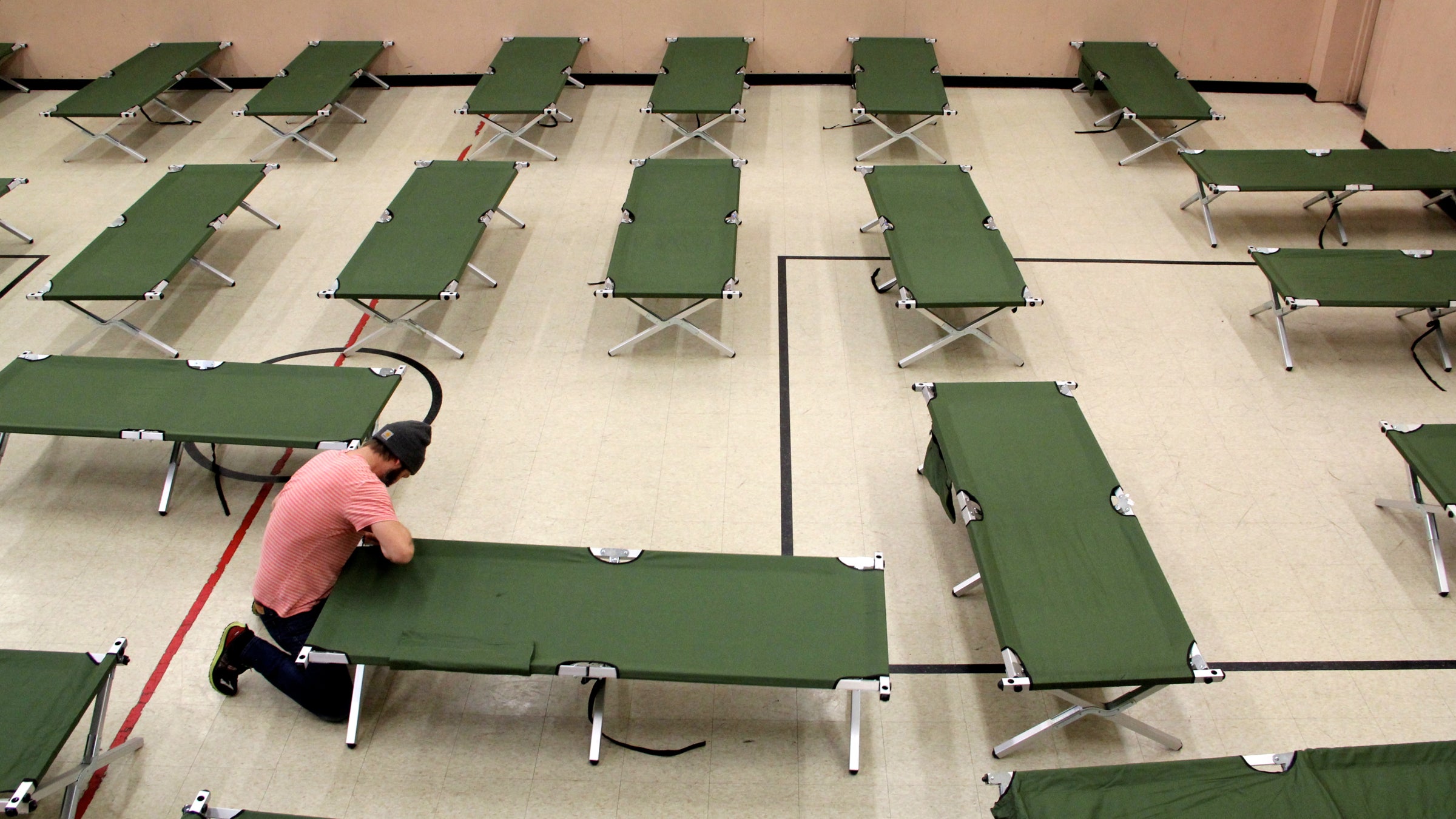  Joel Snyder, housing case manager for the Salvation Army in Norristown, sets up cots in the organization's basement gym. (Emma Lee/WHYY) 
