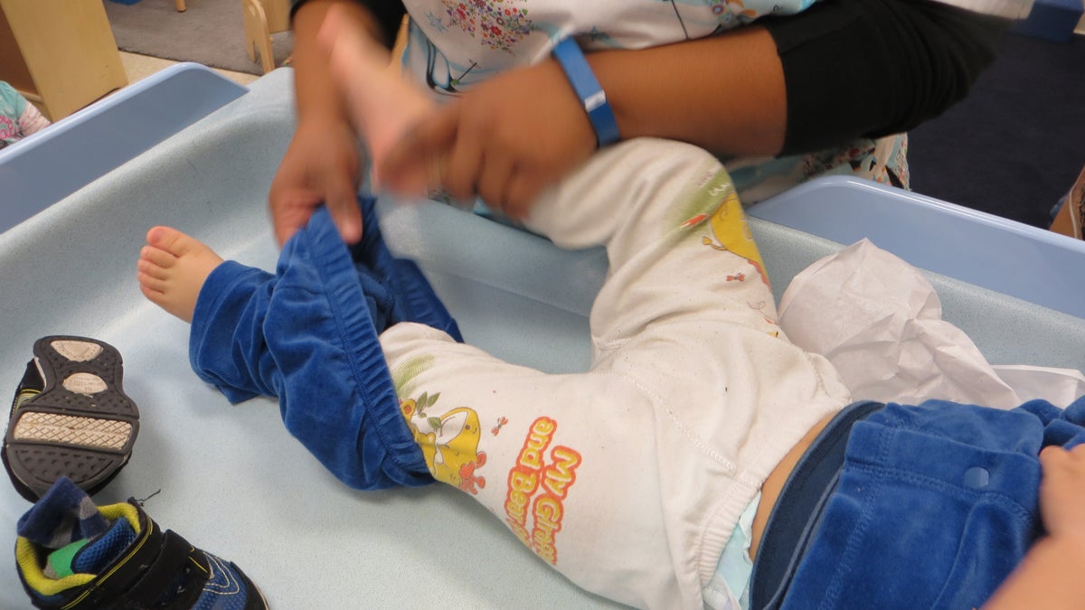 Teachers at the Maternity Care Coalition's Early Head Start prorgram follow a long list of procedures to prevent germ spread at the day care  -- sanitizing diaper-changing tables and wearing gloves to wipe a toddler's nose. (Taunya English/WHYY)