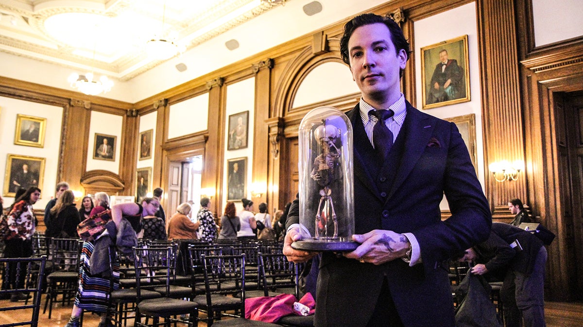 Artist Ryan Matthew Cohn gave a talk at the Death Salon at the Mutter museum. He holds a piece of his collection. (Kimberly Paynter/WHYY)