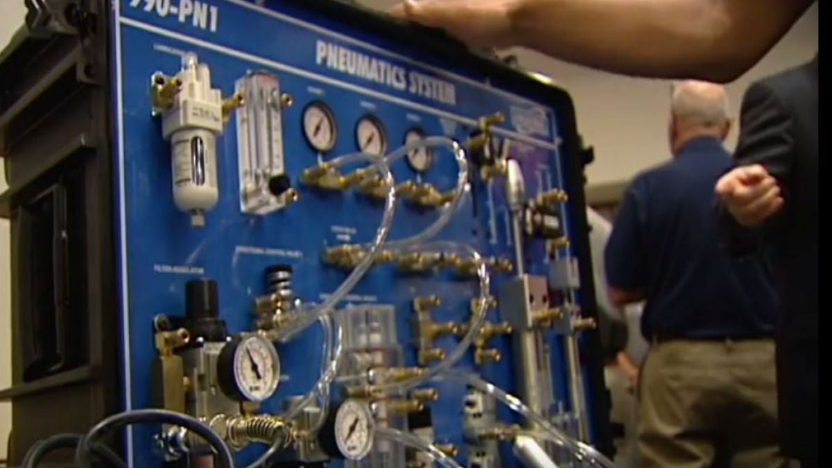 A Del. Tech student demonstrates a pneumatic system used to control an automated manufacturing process after the funding announcement at Del. Tech's Wilmington campus. (Gene Ashley/WHYY)