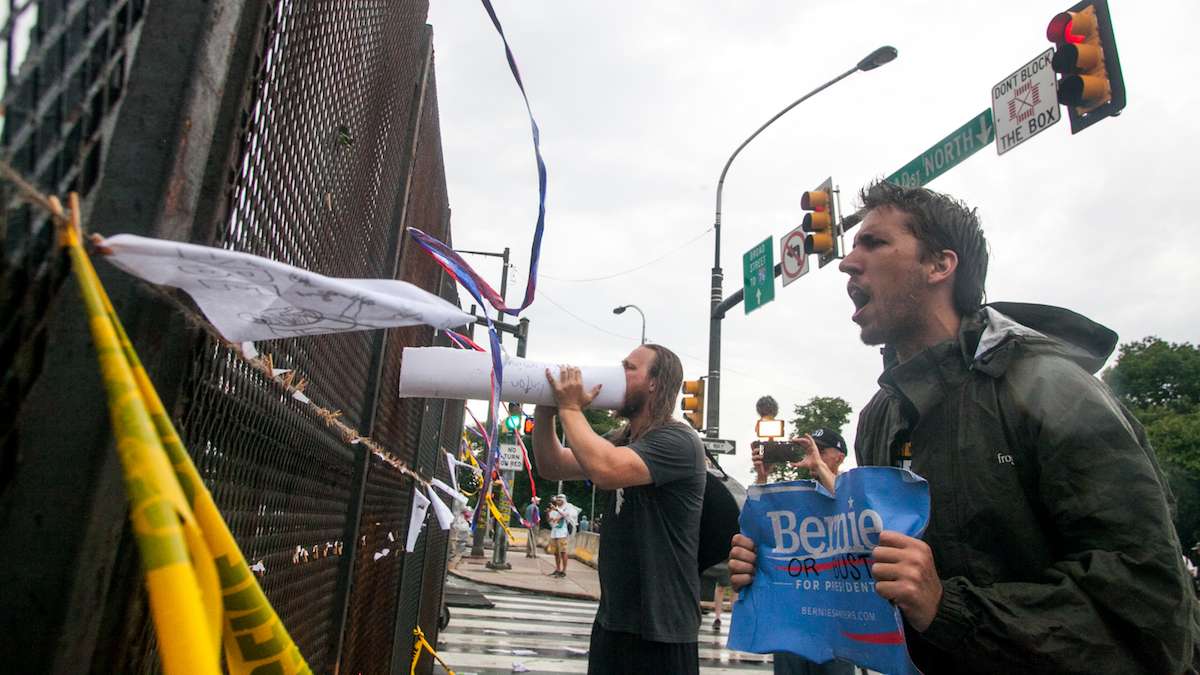 Bernie Sanders supporters yell through the security fence at the Democratic National Convention as delegates arrive for the final night of the event. (Brad Larrison for NewsWorks)