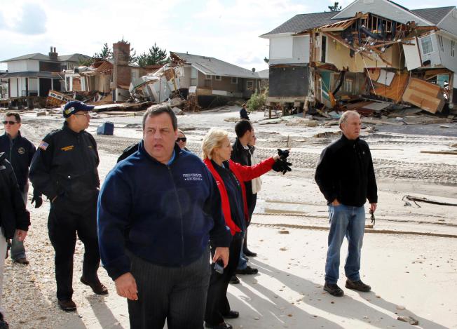  In this Nov. 2, 2012 file photograph, New Jersey Gov. Chris Christie, third from left, walks past damaged homes along the Atlantic Ocean in Mantoloking, N.J. after Superstorm Sandy hit the area on Oct. 29. (AP Photo/Mel Evans, Pool, File)  