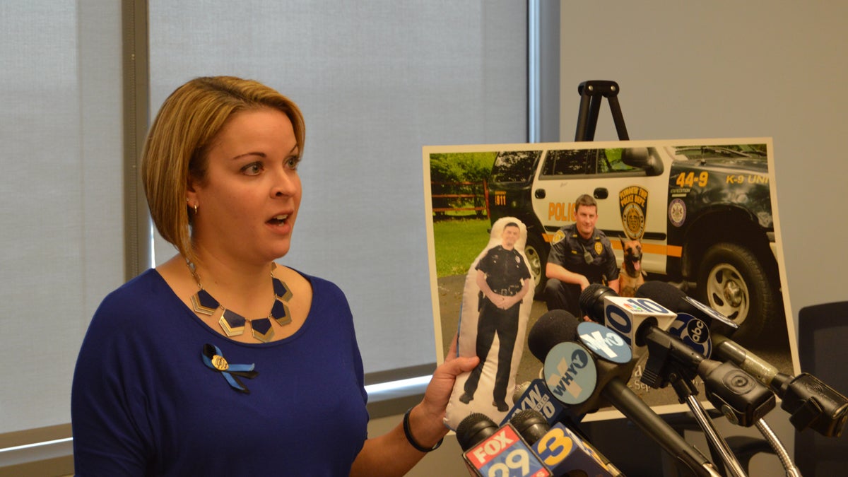  Holding a doll in the image of her slain husband for courage, Lynsay Fox speaks during a news conference Monday. Plymouth Township Officer Bradley Fox was killed in 2012 with a weapon sold to a 'straw' purchaser. (Tom MacDonald/WHYY) 