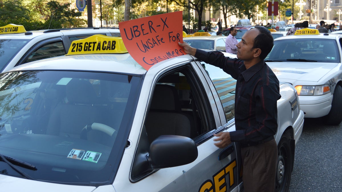 A cab driver places a sign protesting UberX