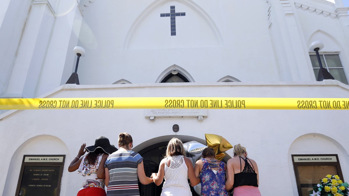 A group of women are shown praying together on the sidewalk in front of the Emanuel AME Church in Charleston