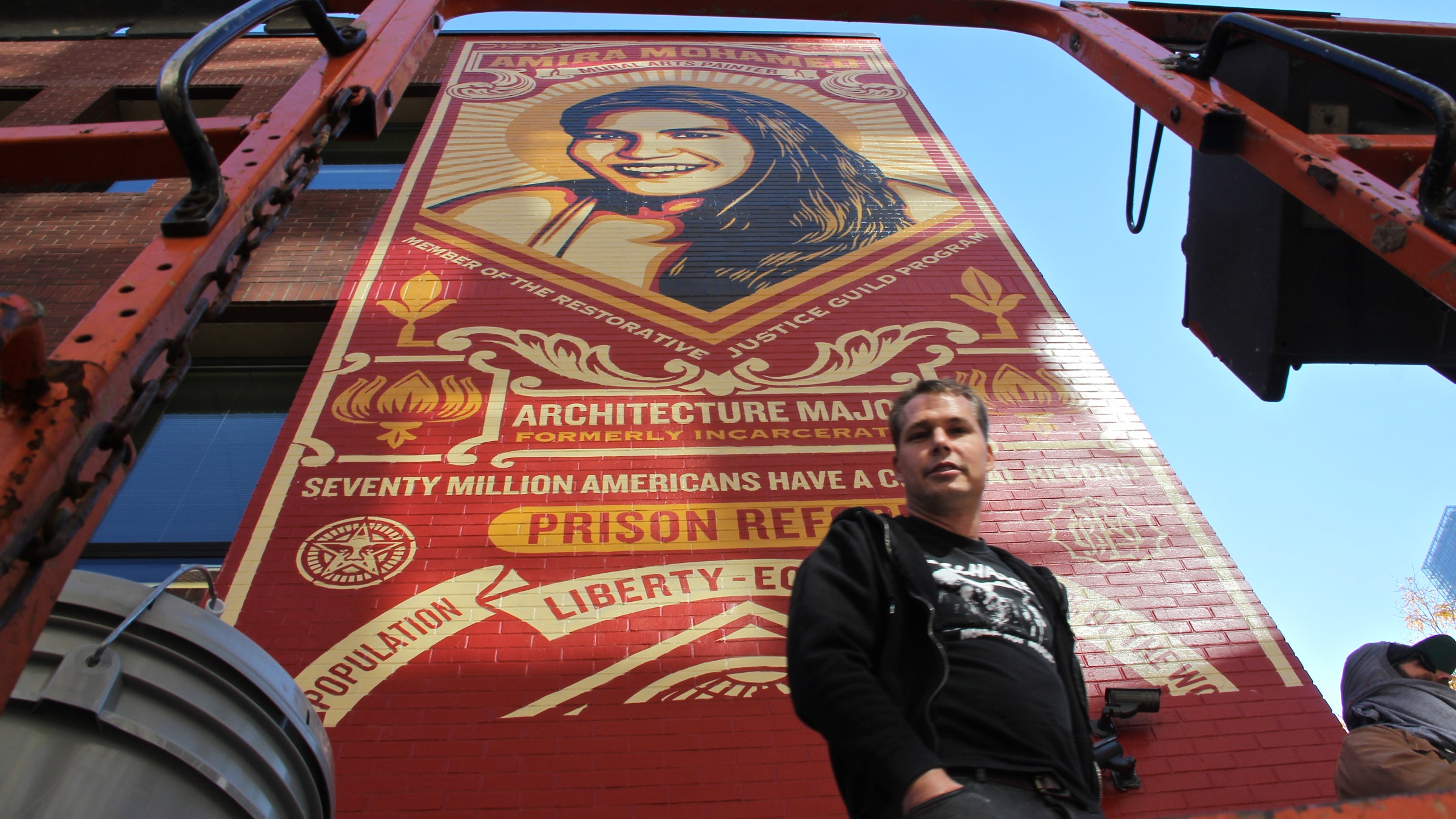 Shepard Fairey prepares to put the finising touches on his mural at the Friends Center at 15th and Race streets. (Emma Lee/WHYY) 