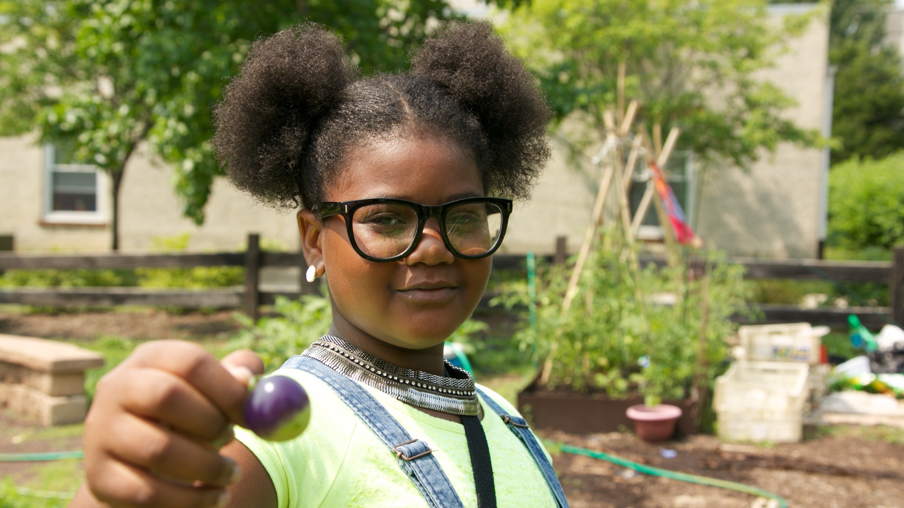  Tahtanique Smith holds up an almost-ripe Cherokee purple tomato grown on the farm. (Nathaniel Hamilton/For Newsworks) 