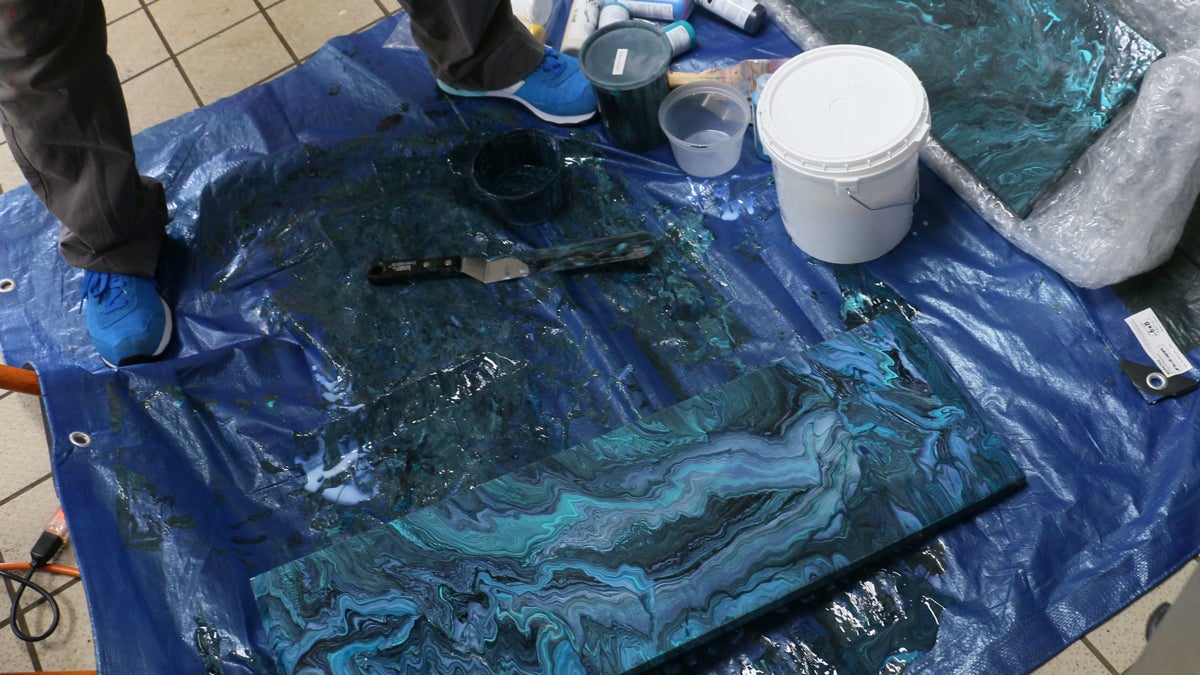 Rebecca Rutstein pours paint in her tiny studio aboard the Nautilus, allowing the motion of the ship to move the paint across the canvas. (Image courtesy of Rebecca Rutstein)