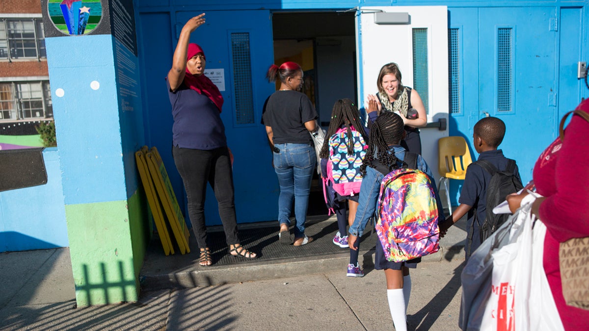 Administrators and teachers give students high-fives and help them navigate their first day of school at Mastery Charter School John Wister Elementary in Philadelphia