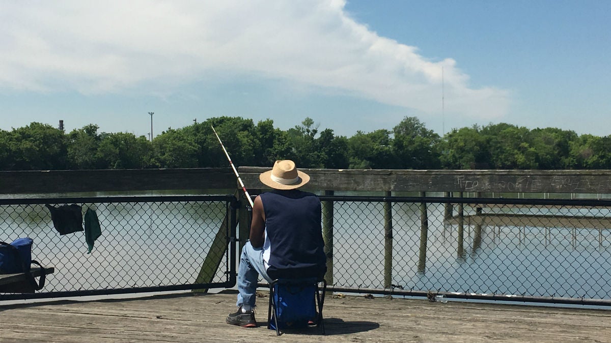An angler fishes off a dock along the Christina River in Wilmington. (Mark Eichmann/WHYY)