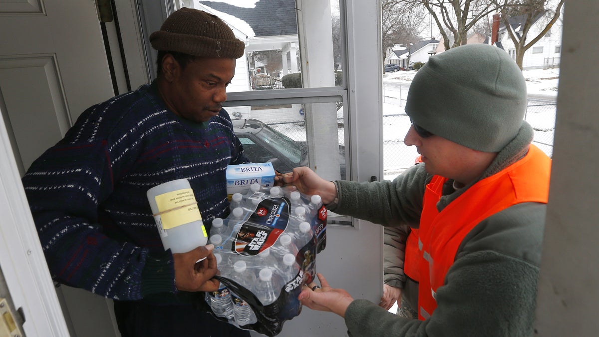  Louis Singleton receives water filters, bottled water and a test kit from Michigan National Guard Specialist Joe Weaver as clean water supplies are distributed to residents, Thursday, Jan. 21, 2016 in Flint, Mich. The National Guard, state employees, local authorities and volunteers have been distributing lead tests, filters and bottled water during  the city's drinking water crisis.  (AP Photo/Paul Sancya) 