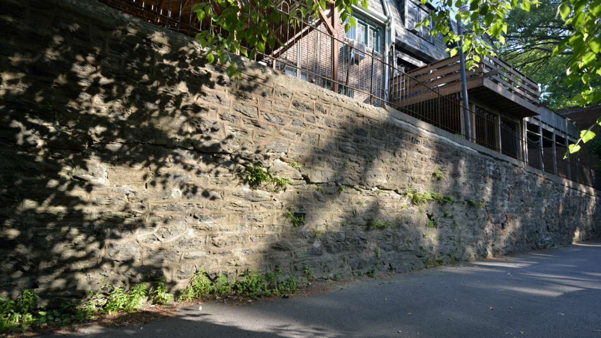  The 550-foot stone-masonry retaining wall that separates the rear alley of houses along West Penn Street from the common driveway of homes along Midvale Avenue is leaning, cracked and unsafe. (Bas Slabbers/for NewsWorks, file) 
