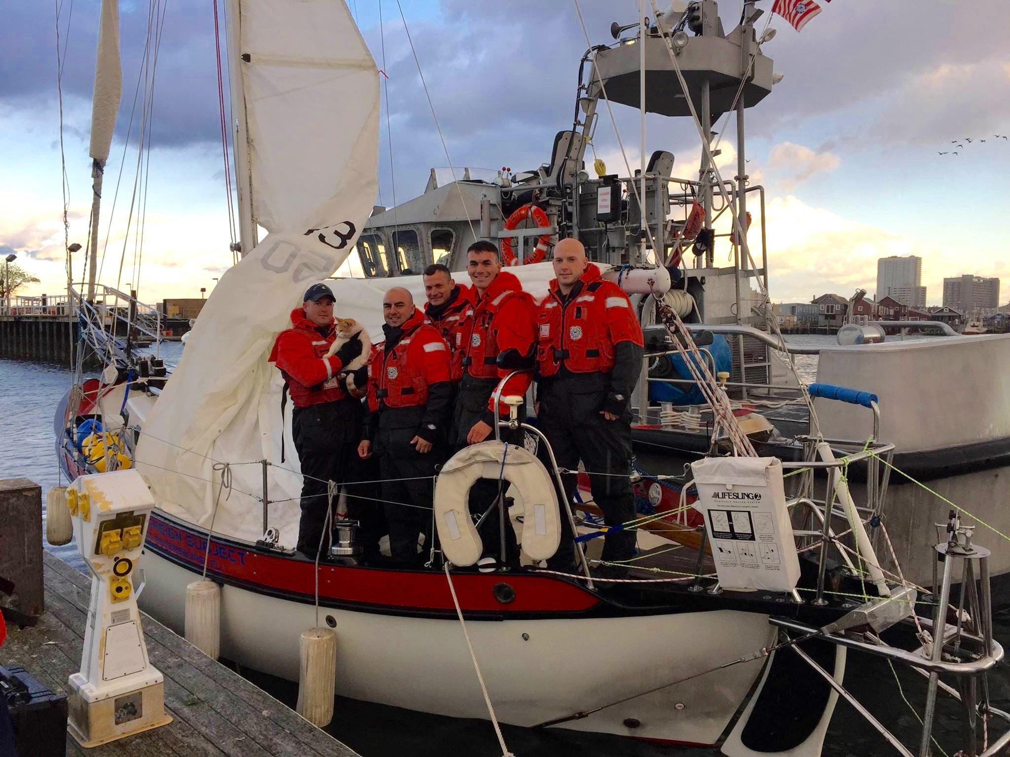  A Coast Guard rescue crew poses on a sailboat that was towed ashore along with its resident cat. (Image courtesy of the U.S. Coast Guard) 