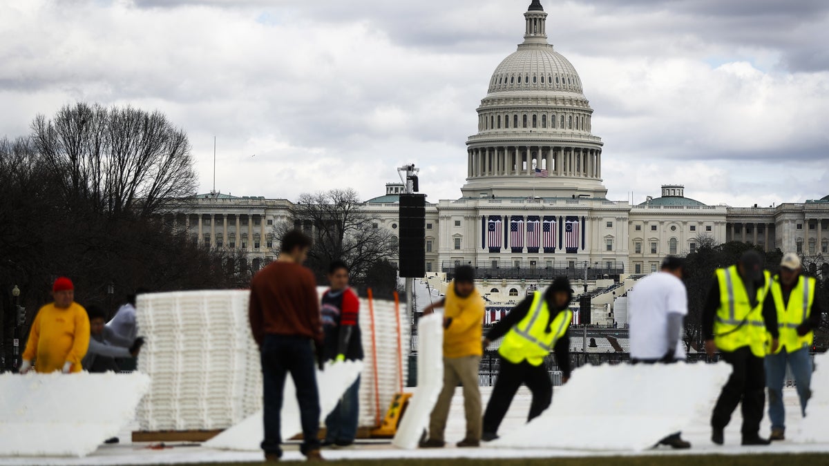 Workers place plastic flooring on the grass of the National Mall in Washington